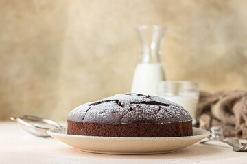 Chocolate sponge flourless cake with sugar powder, light concrete background. Brownie cake. Toned image.