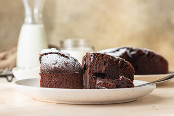 Chocolate sponge flourless cake with sugar powder, light concrete background. Brownie cake. Toned...