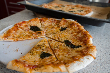 sliced homemade pizza with basil on a plate