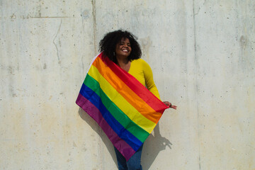 Obraz na płótnie Canvas very happy african-american lesbian woman with the gay pride flag on her body on a grey background