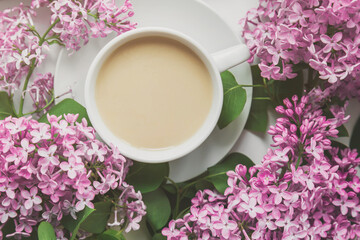 spring composition flat lay white cup of coffee, pink lilac beautiful bouquet of lilacs, old book, concept of spring and comfort 
