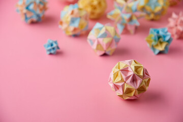 Set of multicolor handmade modular origami balls or Kusudama Isolated on pink background. Visual art, geometry, art of paper folding, paper crafts. Close up, selective focus, copy space.