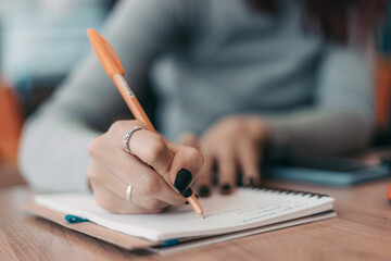 girl writes in a notebook with a pen. blurred background