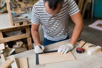 Close up of Man carpenter measuring a wooden board with a ruler with scale in workshop. Joinery work on the production and renovation of wooden furniture. Small Business Concept