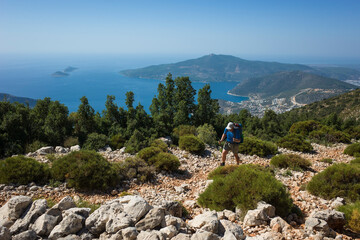 Fototapeta na wymiar Hiking Lycian way. Man is trekking on stony path high above Mediterranean sea coast on Lycian Way trail from Kalkan to Bezirgan, Outdoor activity in Turkey