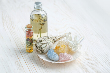 Healing gemstones, white sage bundle, magic bottles on wooden table. holy sage, incense for fumigation, cleaning, good energy. Wiccan Witchcraft. Crystal Ritual, esoteric spiritual practice concept 