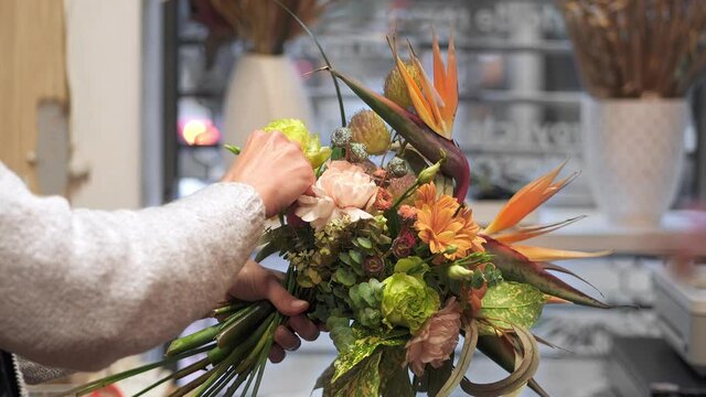 Florist making a bouquet in a flower shop, moving flowers for better composition