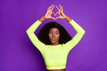 Obraz na płótnie Canvas Photo of young pretty charming dark skin girl pout lips showing heart sign wear sport suit isolated on violet color background