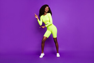 Fototapeta na wymiar Photo of young dancer lady have fun look empty space wear green shirt shorts footwear isolated purple background