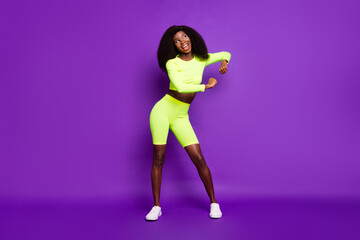 Photo of young lady enjoy dance open mouth look empty space wear green shirt shorts sneakers isolated violet background