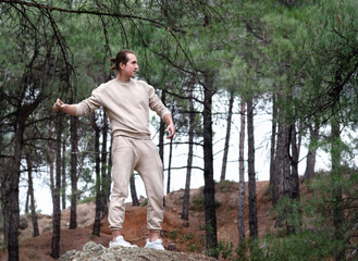 Young man throwing rocks randomly in the forest, finding balance and mental health concept. Copy...