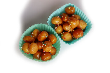 Traditional italian fried Struffoli with honey and sugar sprinkles  isolated on white background