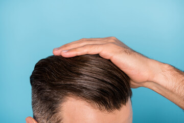 Fototapeta premium Cropped photo of young handsome man fixing his hairstyle silky healthy hair isolated on blue color background