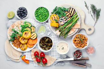 Delicious grilled vegetables with sauces and snacks served on light gray background.