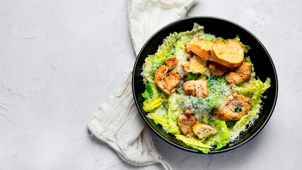 Classic caesar salad with grilled chicken on gray background.