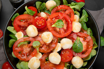 Delicious Italian caprese salad with sliced tomatoes and mozzarela on dark background.