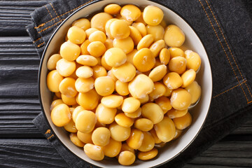 Salted yellow lupine beans close-up in a bowl on the table. horizontal top view from above