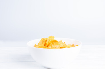 Potatoes chips in white bowl on wood surface