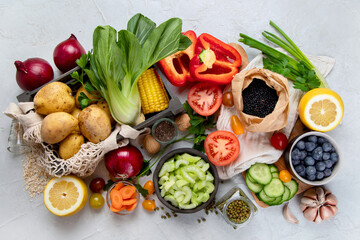 Selection of fresh raw vegetables, fruits and beans on light gray background.