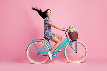 Full length body size profile side view of lovely cheerful girl riding bike having fun fast speed adventure isolated on pink pastel color background