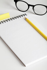 office table desk, workspace with notebook, yellow pencil, erasing and glasses. Minimal concept. Flat lay, top view, copy space.