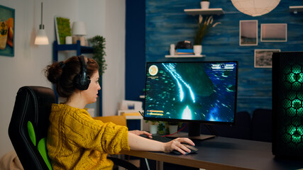 Fototapeta premium Professional gamer with headset starting to play online video game in living room. Pro esport team player streamer playing gaming tournament on powerful RGB computer, using modern streaming technology