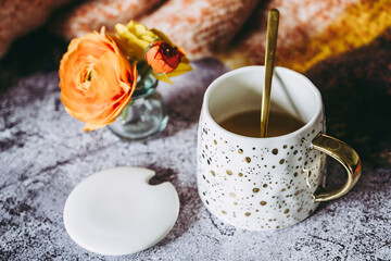 Mug avec du thé sur la table avec un bouquet de fleurs renoncules colorées
