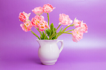 bouquet of pink tulips in a vase on a purple background