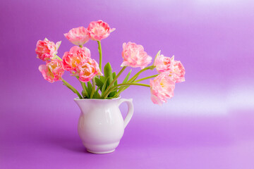 Fototapeta na wymiar bouquet of pink tulips in a vase on a purple background