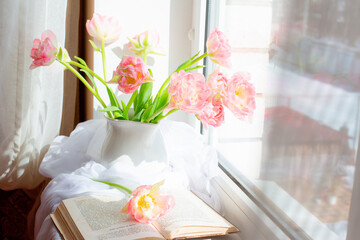 still life a vase with tulips and an old book on the window