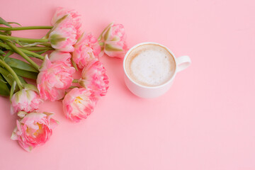 Fototapeta na wymiar pink tulips and a cup of coffee on a pink background
