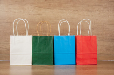 Colorful paper shopping bags on the floor against a wooden wall background