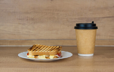 big sandwich with ham, cheese, tomatoes and disposable coffee cup on toasted bread