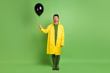 Full length body size view of attractive serious confident guy wearing raincoat holding air ball...