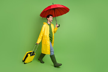 Full size profile side photo of young happy positive man go walk hold baggage and umbrella isolated...