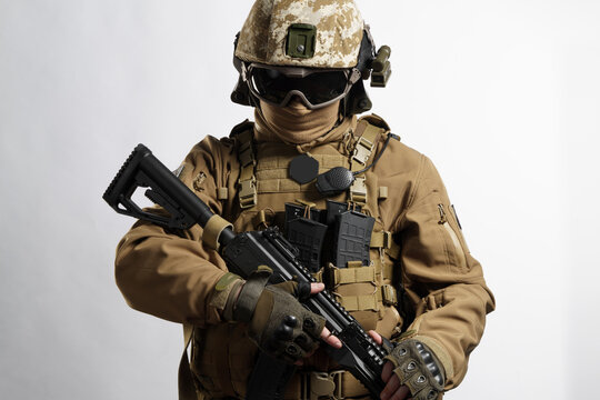 Male soldier in tactical equipment and uniform (coyote brown color) . Shot in studio on a white background
