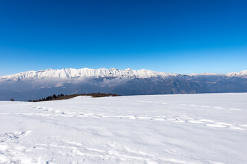 Fototapeta na wymiar Mountain Range of Monte Baldo and Adamello in winter with snow, view from the Lessinia Plateau (Altopiano della Lessinia) Verona. Veneto and Trentino Alto Adige, Italy, Europe.