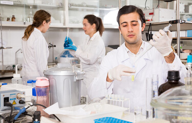 Intelligent student performing experiments in university laboratory, using mechanical lab pipette...