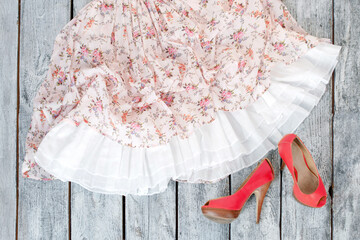 Pair of woman shoes and pink skirt on a wooden floor. Fashionable women's clothing, shopping or...