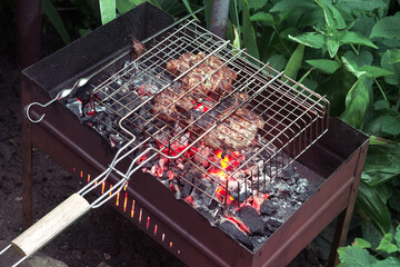 marinated meat in grill basket and on flat skewer of steel, cooked on red-hot charcoal in...