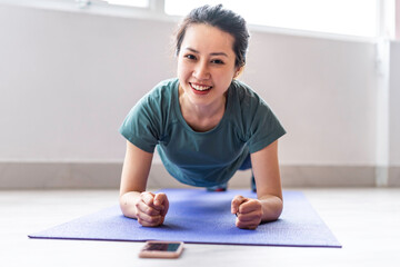 Young woman doing exercise at home with cheerful expression