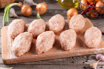 Raw Frozen lazy cabbage rolls lie on a wooden board on the kitchen table with vegetables. Frozen food