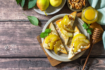 Summer healthy breakfast or snack, antipasto. Grill toast with caramelized pear, honey, nuts and cheese ricotta on a wooden rustic table. Top view flat lay. Copy space.