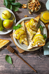 Summer healthy breakfast or snack, antipasto. Grill toast with caramelized pear, honey, nuts and cheese ricotta on a wooden rustic table. Top view flat lay. Copy space.