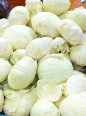 Fototapeta na wymiar White cabbage heads stacked for sale at the groceries, big whole ripe round vegetables background - Calcium food, vitamins rich, cheap healthy food