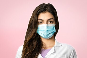 A scientific researcher in a surgical gown and mask. In a pink background. Perfect shot for pandemic, research, vaccine.