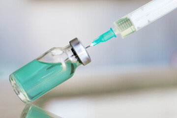 Vial filled with liquid vaccine in medical lab with syringe. medical ampoule and syringe on the glass surface