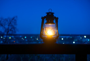 Relaxing background with ancient kerosene lamp on the table against the landscape with bokeh.