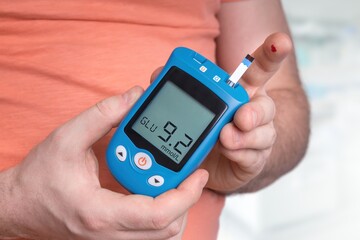 Man is checking blood sugar level with glucose meter