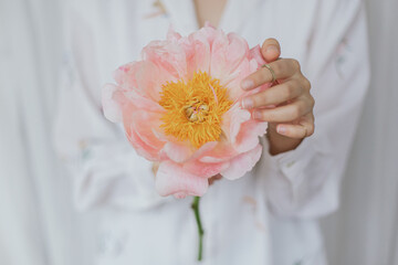 Beautiful stylish woman holding pink peony. Young female in boho floral shirt with flower in hands © sonyachny